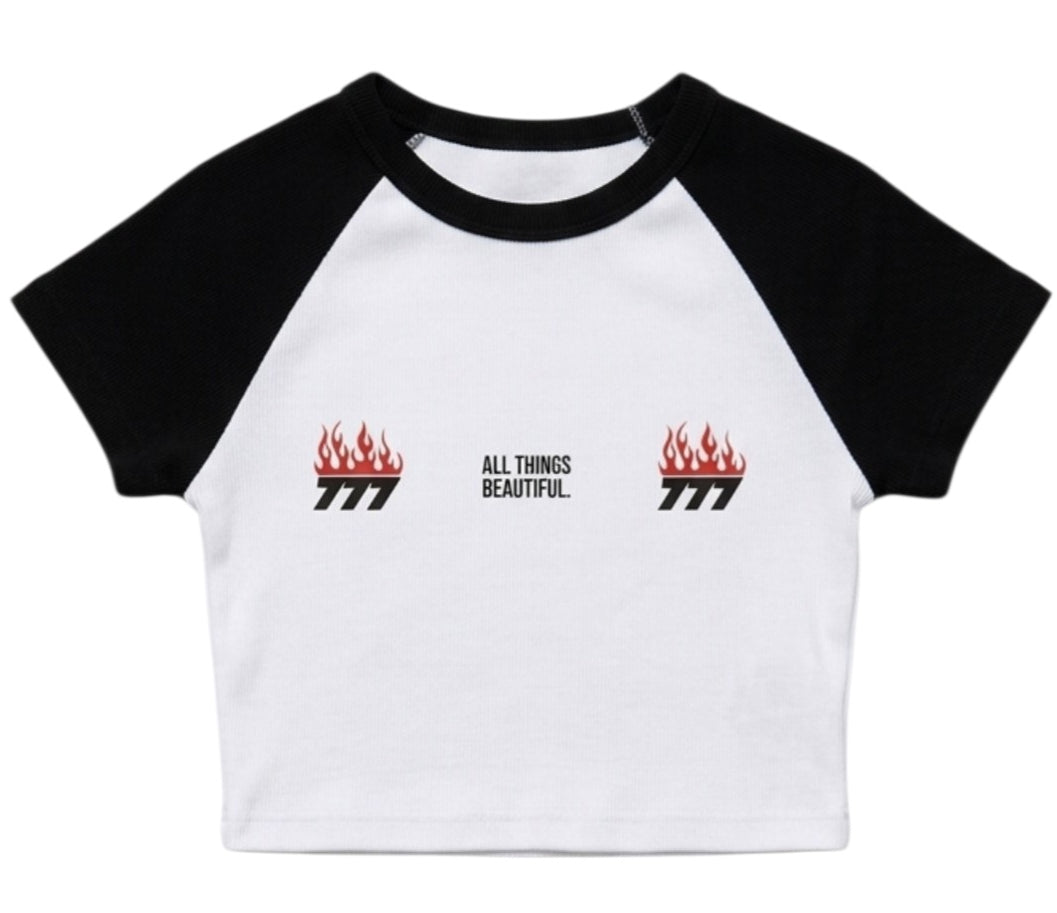 White-and-black raglan baby tee with small flame logos and “ALL THINGS BEAUTIFUL” text