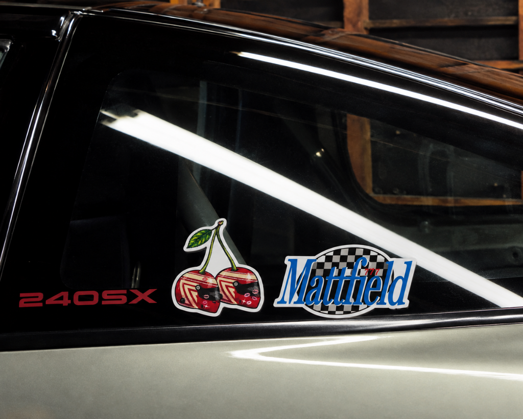 Cherry and blue-script car sticker on black vehicle body panel