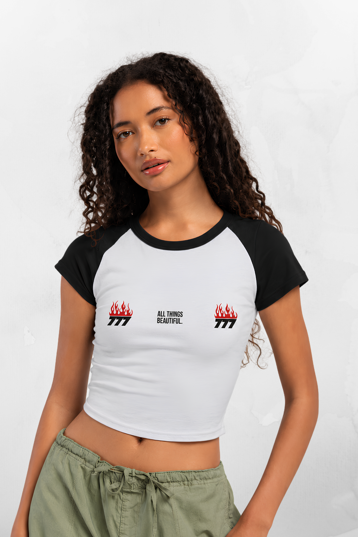 Black-sleeve white raglan baby tee with small flame logos and “ALL THINGS BEAUTIFUL”
