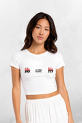 White baby tee with small red flame logos and “ALL THINGS BEAUTIFUL” on front